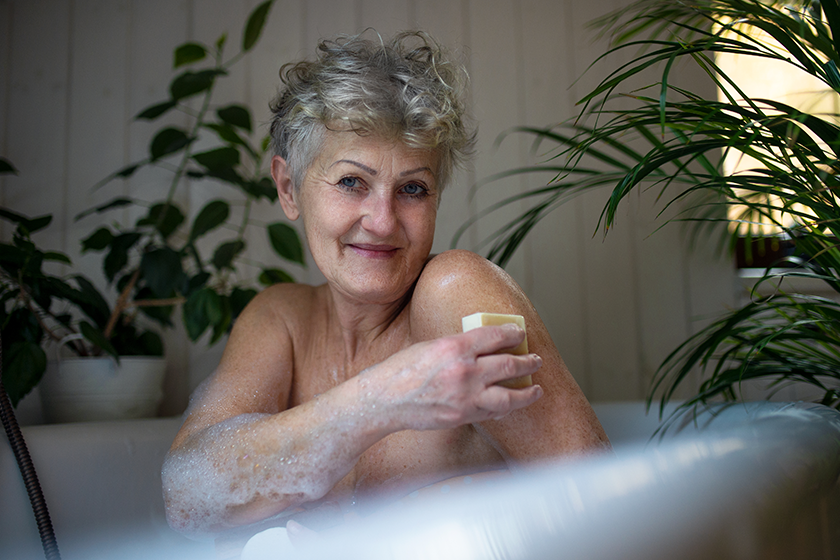 Contented senior woman washing in bubble bath