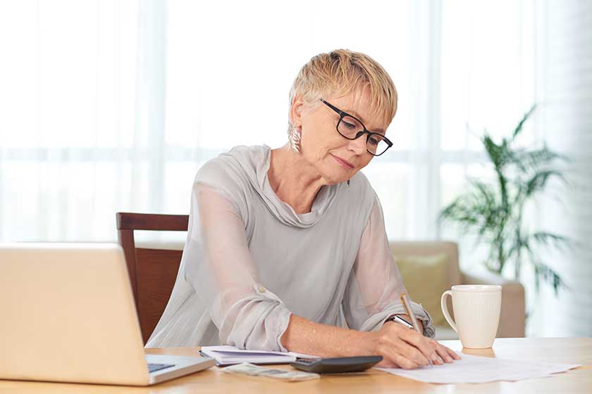 Elegant senior woman writing down household monthly expenses