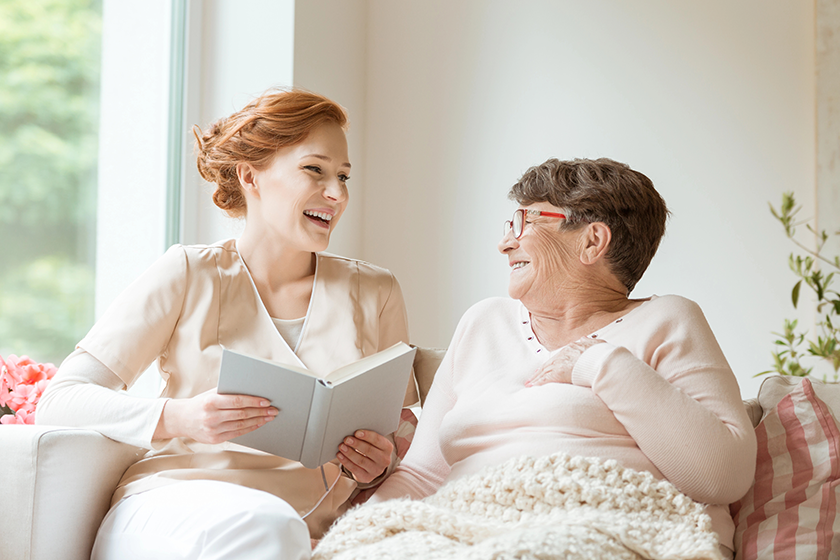 happy-nurse-reading-funny-book-her-elderly-patient