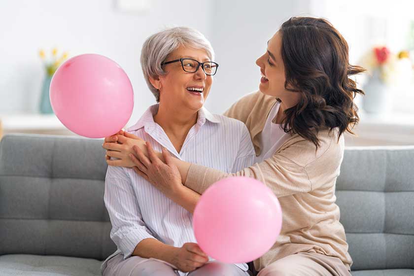 Happy woman's day! Beautiful young woman and her mother with air balloons at home