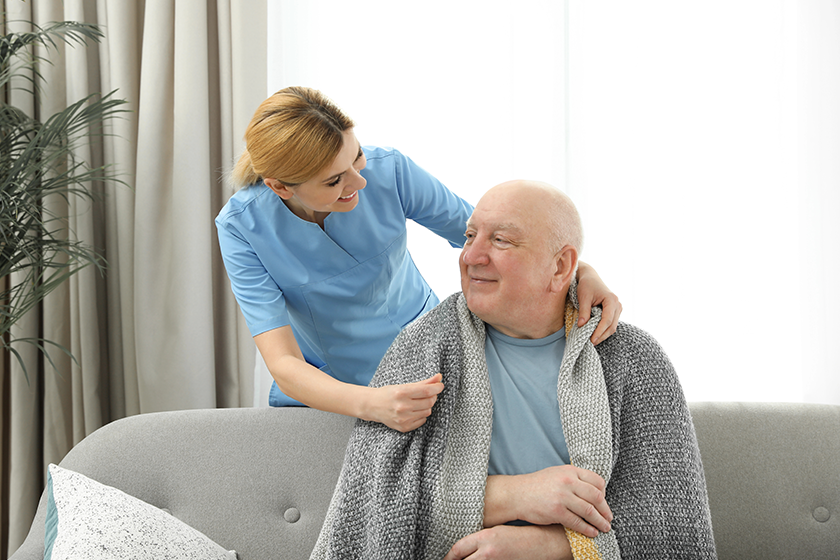 Nurse covering elderly man with blanket