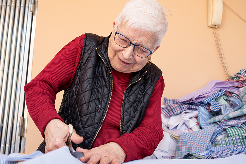 Older woman cutting gown fabrics to sew